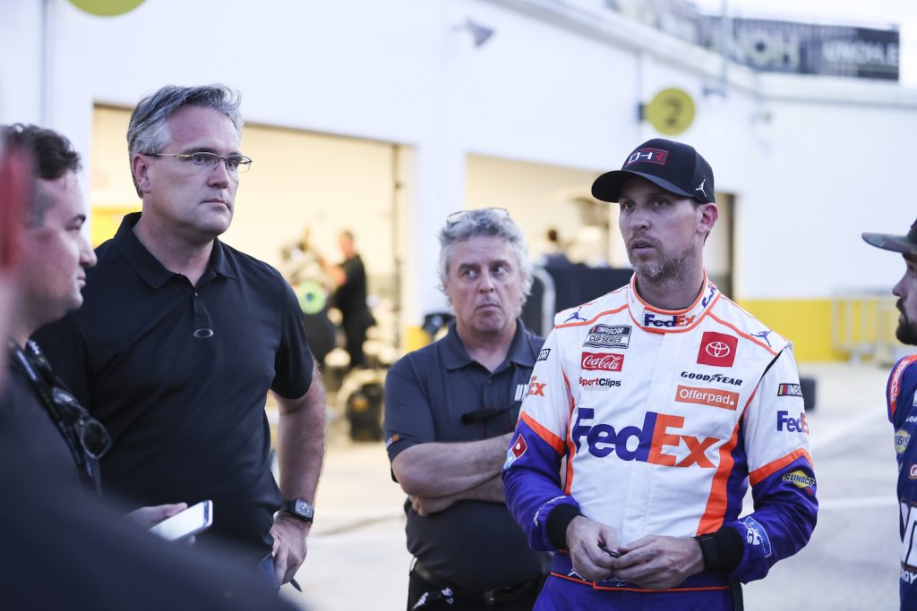 Denny Hamlin, team owner and Driver of the #11 NASCAR Next Gen car, talks with NASCAR personnel. Some drivers are complaining that NASCAR’s Next Gen Cars Are Too Hot To Drive | Photo by James Gilbert/Getty Images