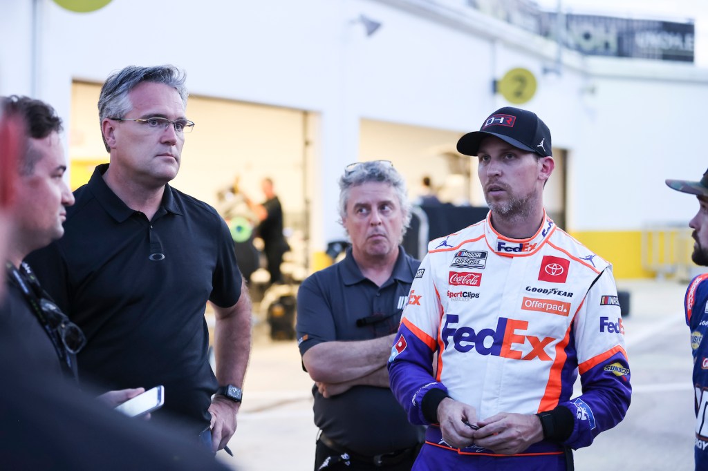 Denny Hamlin, team owner and Driver of the #11 NASCAR Next Gen car, talks with NASCAR personnel. Some drivers are complaining that NASCAR’s Next Gen Cars Are Too Hot To Drive | Photo by James Gilbert/Getty Images