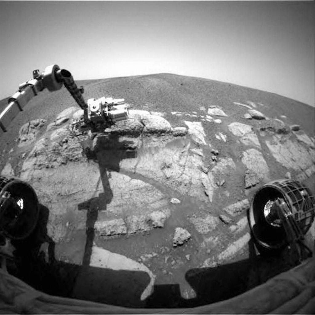 black and white image taken from a Mars rover of the rover arm grabbing some samples