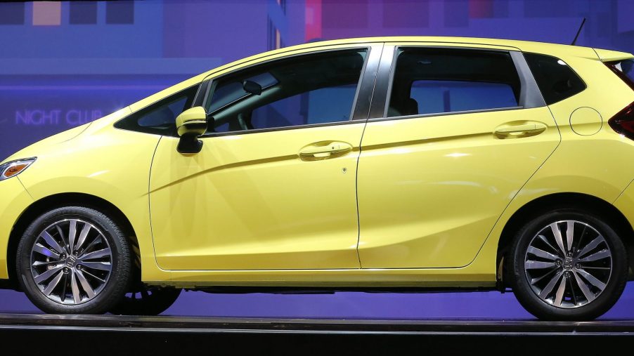 A yellow 2015 Honda Fit subcompact car shot in profile at an auto show
