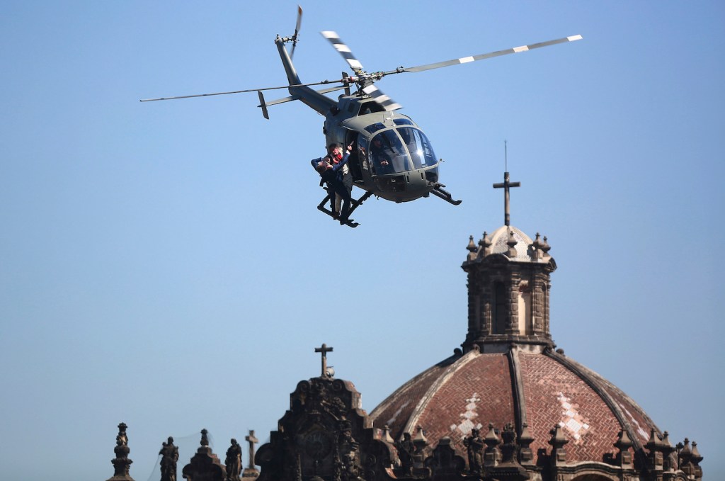 This is a picture of stuntmen as they perform a battle hanging from a helicopter during the filming of the James Bond movie 'Spectre' at Zocalo Main Square in Mexico City, Mexico. The Spectre fight is one of many memorable James Bond helicopter scenes. | Hector Vivas/LatinContent/Getty Images