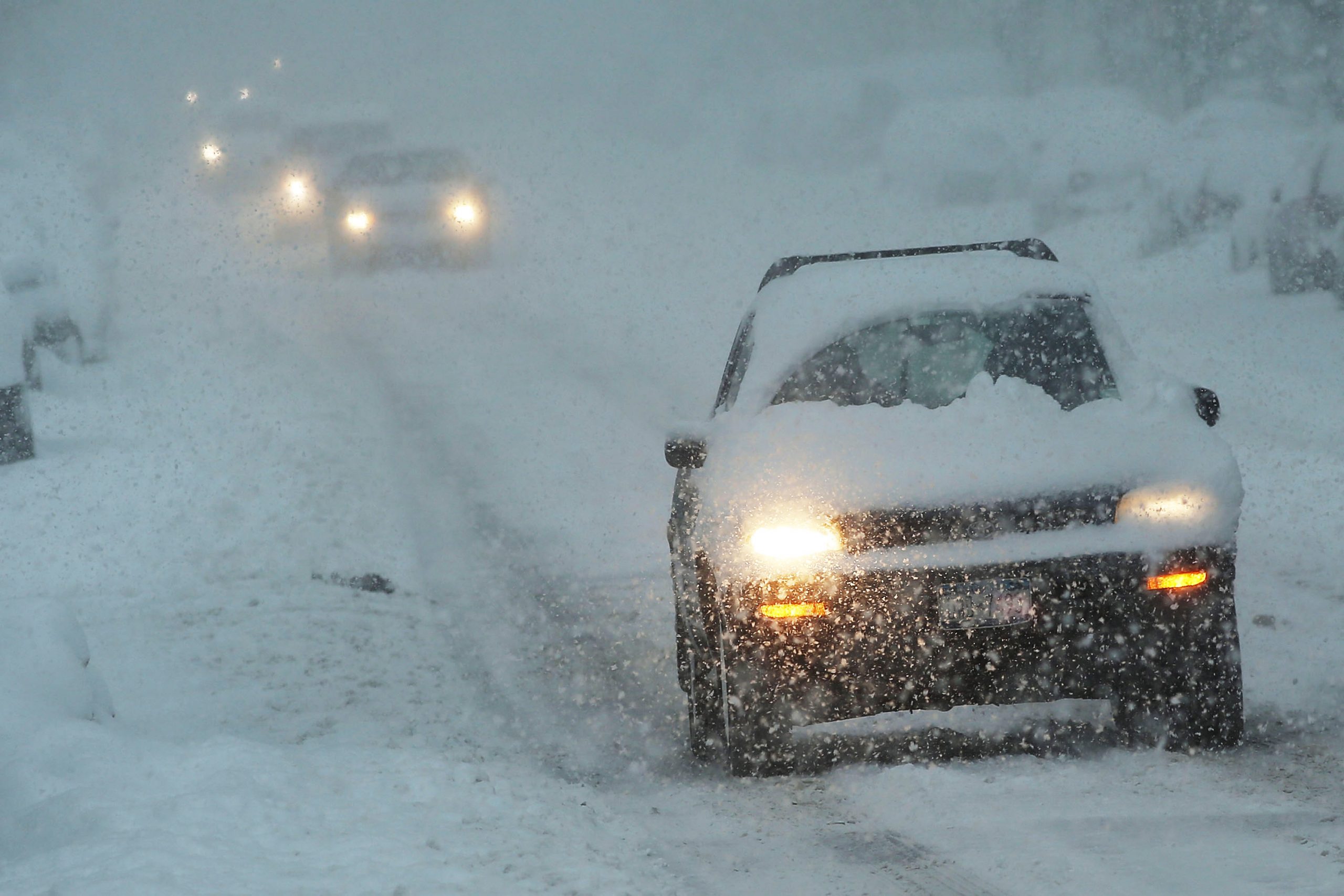 A car wades cautiously through a viscous blizzard in New York