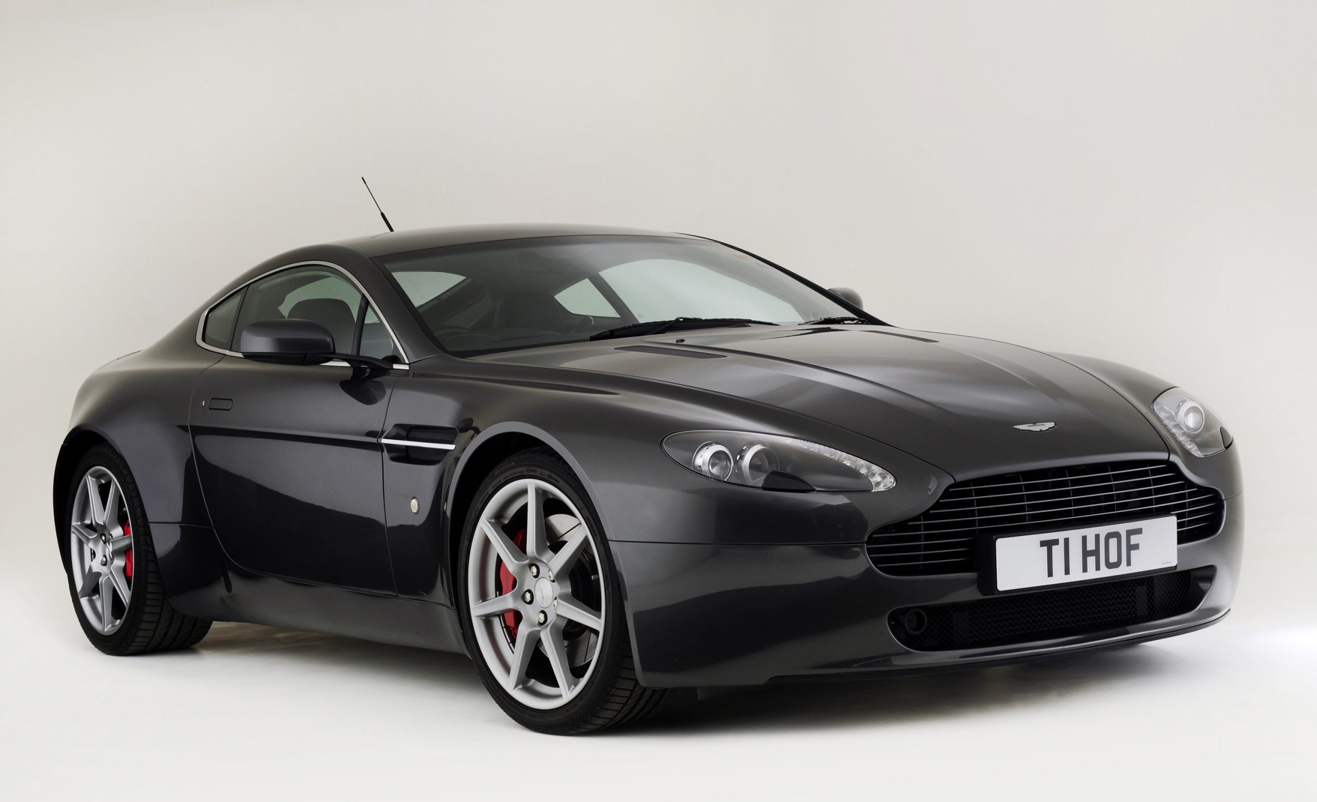 A black Aston Martin Vantage coupe shot from the front 3/4 angle in a studio booth