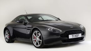 A black Aston Martin V8 Vantage shot from the front 3/4 angle in a studio booth