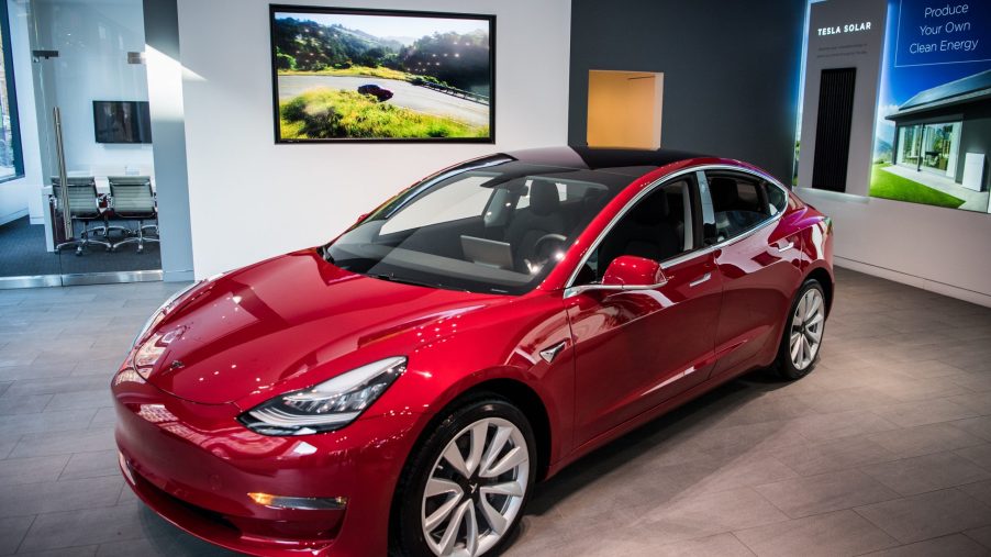 A red Tesla Model 3 in a showroom