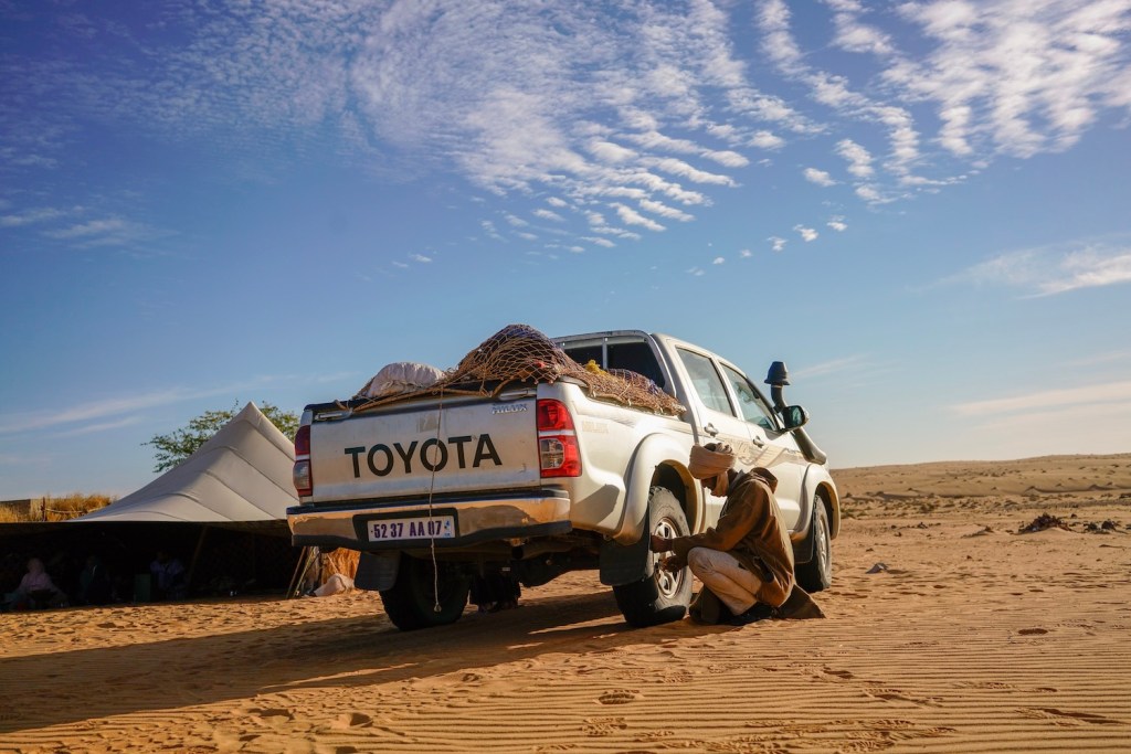 A driver for hire adjusts a Toyota truck's tire pressure for Saharan sand dunes in Oudane Mauritania. Instead of an electric Toyota Tundra, the world's largest automaker developed a next generation internal combustion drivetrain. | David Degner/Getty Images