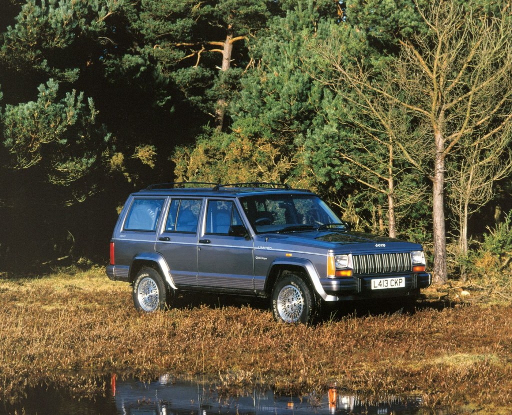 Gray 1993 Jeep Cherokee parked next to a forest 