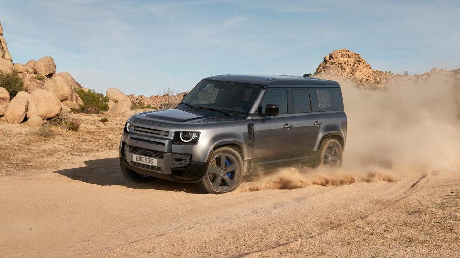 Gray 2021 Land Rover Defender driving by large boulders