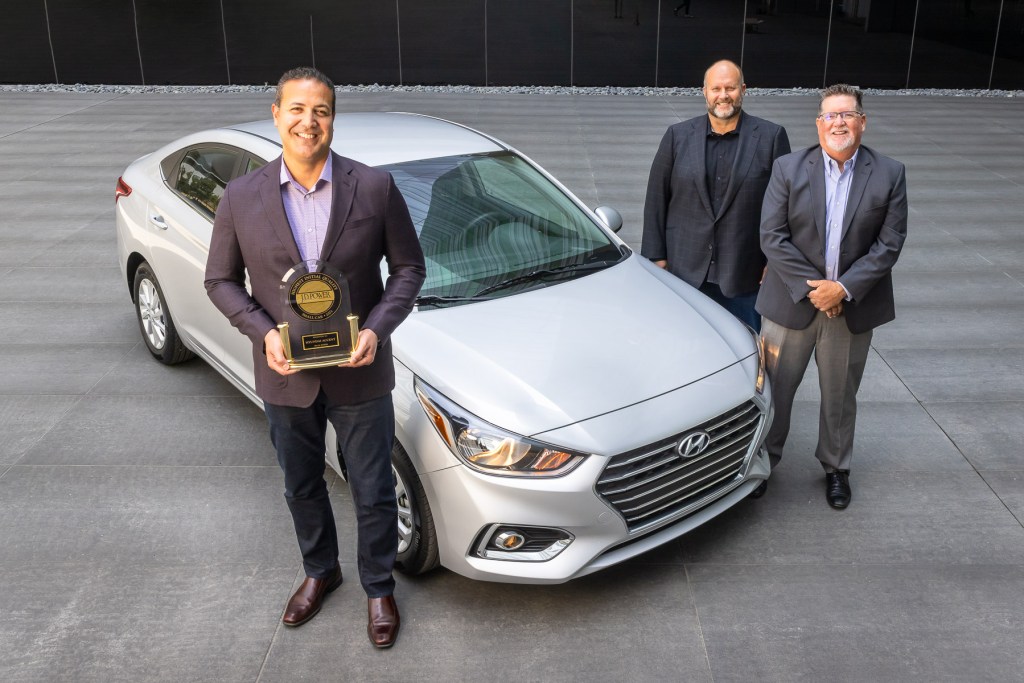 Hyundai executives standing next to a silver 2021 Hyundai Accent with the J.D. Power Initial Quality award