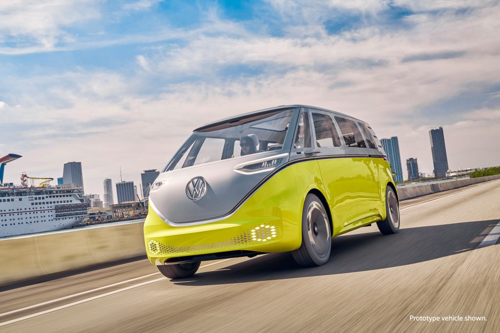 A yellow Volkswagen ID.Buzz concept microbus drives down a road during the day