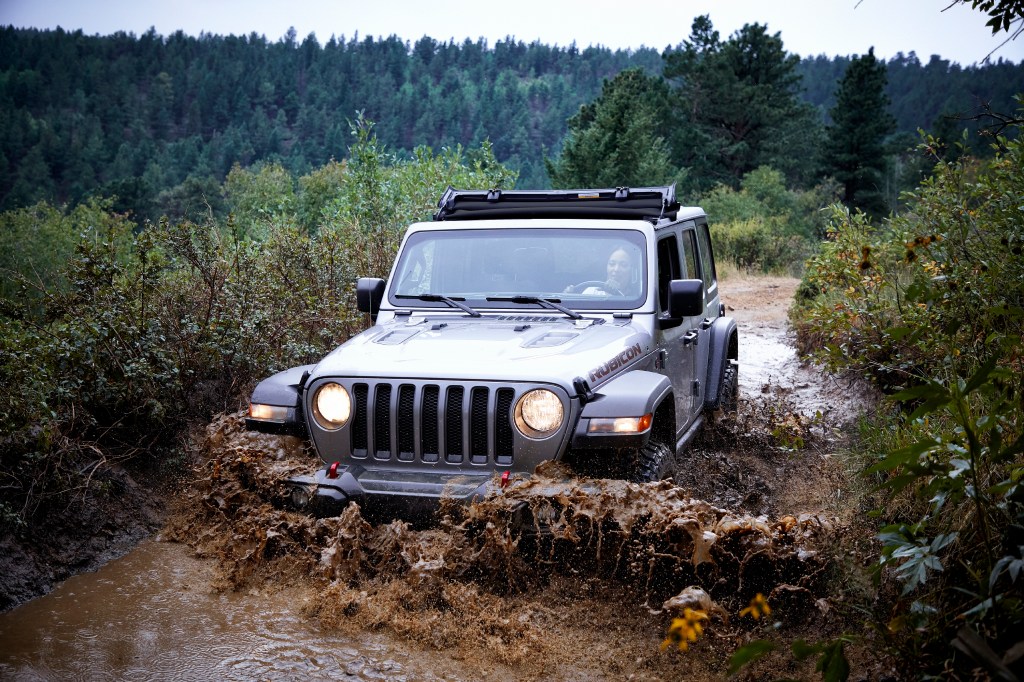 The 2021 Jeep Wrangler works its way through a muddy, forested trail