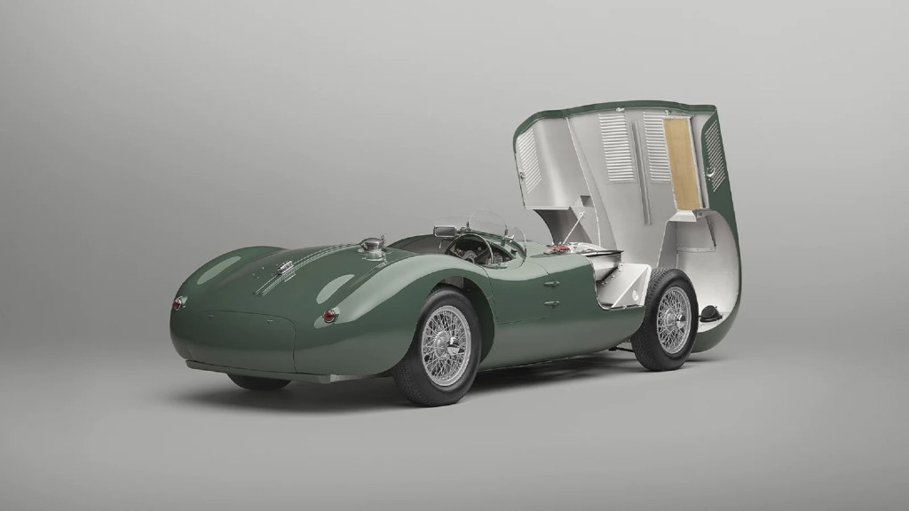 The rear 3/4 view of a green Jaguar C-Type Continuation with its hood open