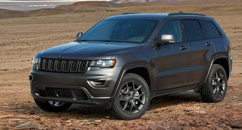 A black Jeep Grand Cherokee SUV is parked off-road. 