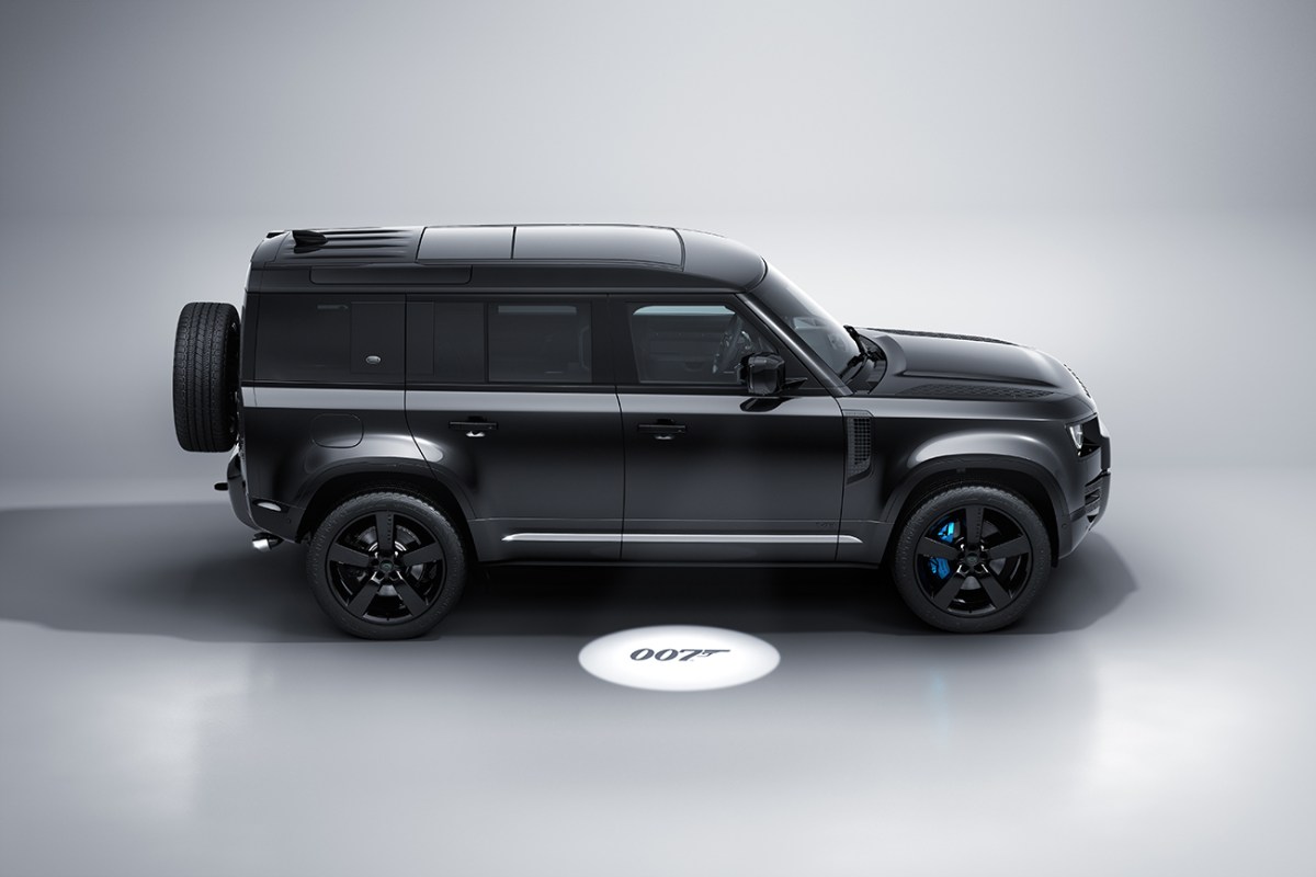 The Land Rover Defender V8 Bond Edition seen in a side view with a puddle light featuring the "007" logo. 