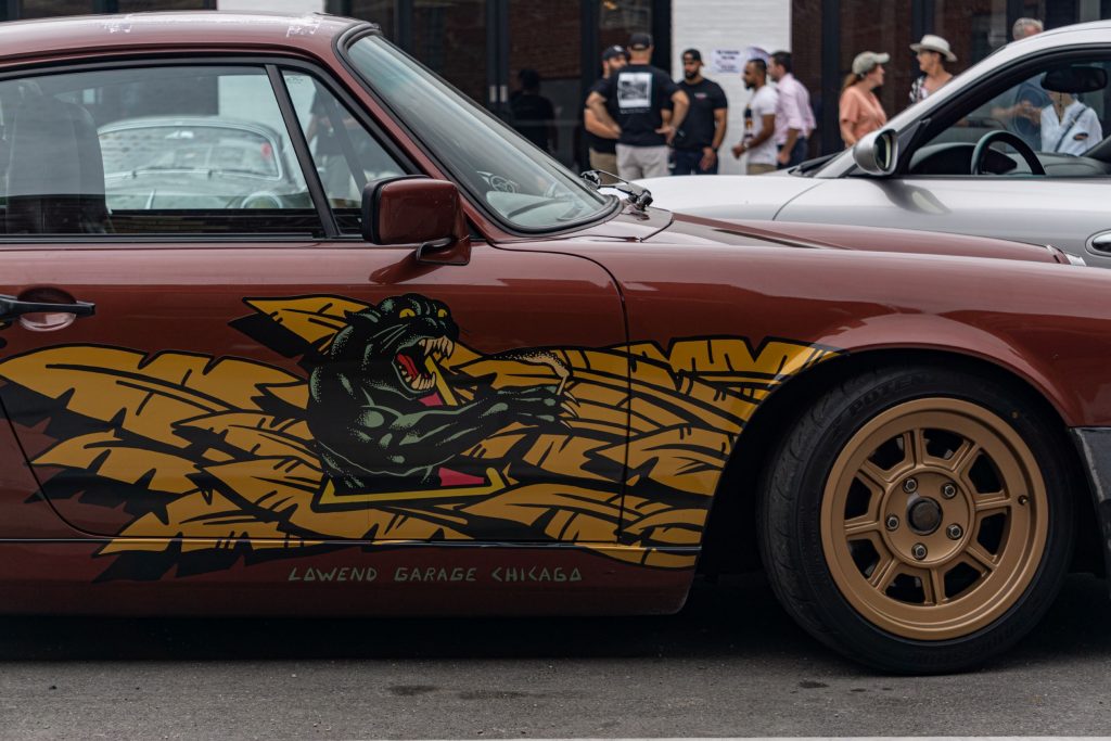 The side view of Lowend Garages' custom maroon Porsche 964 with gold-striped-black-panther decal