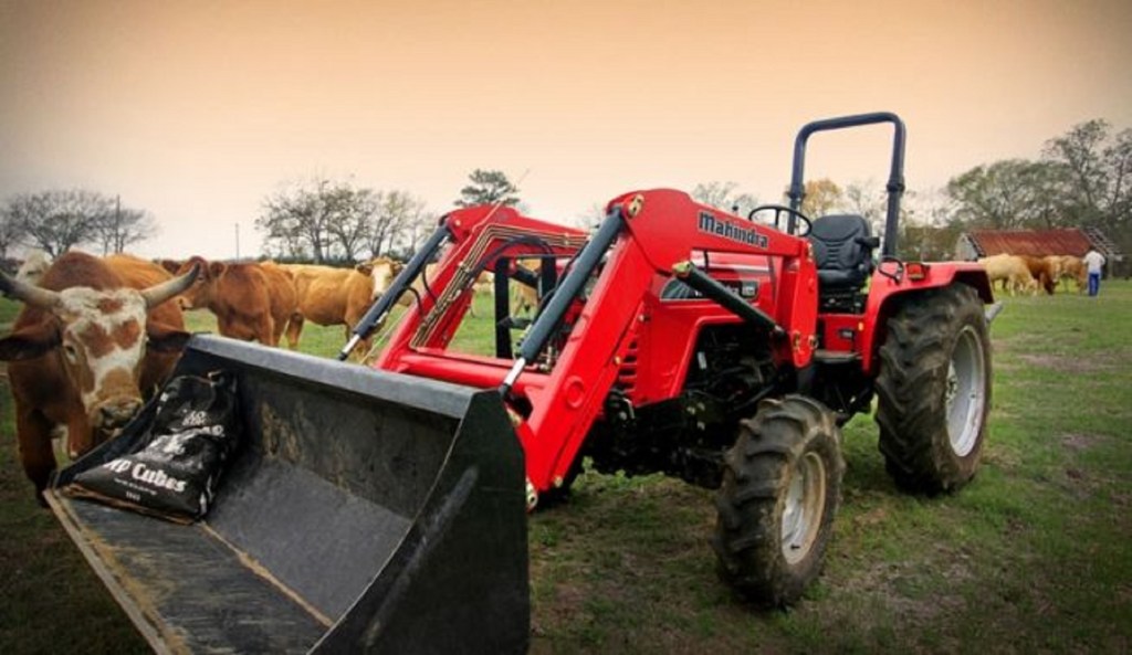 A red Mahindra 4540 4WD compact utility tractor amongst some cows