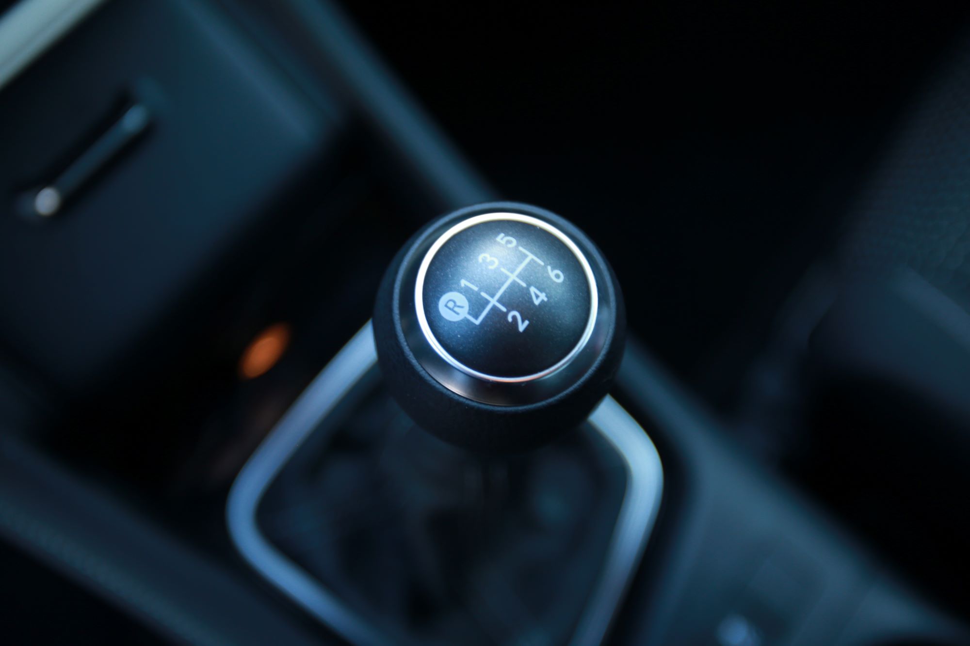 A six-speed manual transmission shifter gear select inside a vehicle with black interior