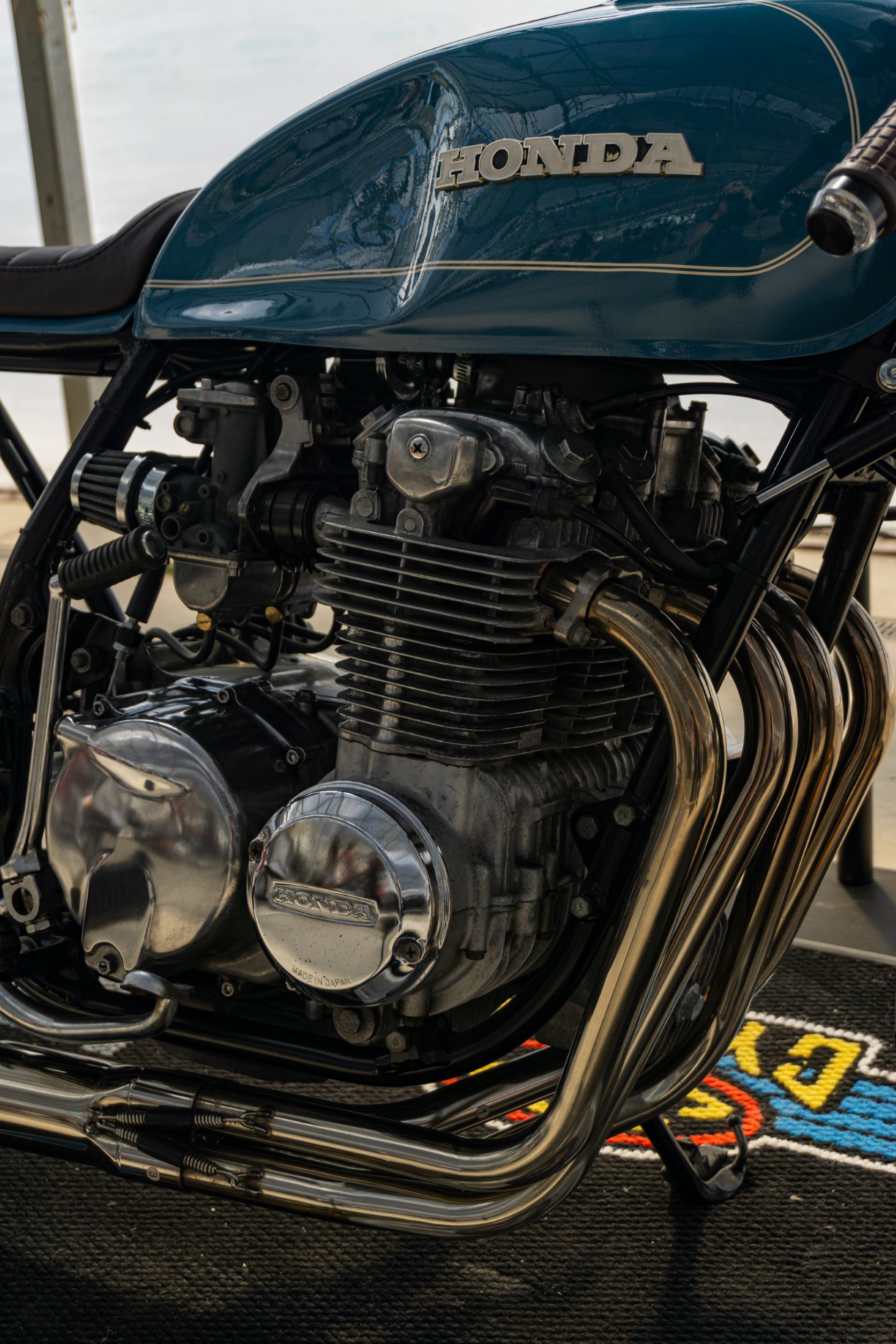 A close-up view of Mateusz Kubak's custom 1974 Honda CB550 cafe racer's engine and exhaust
