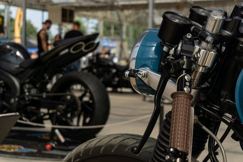 The side view of Mateusz Kubak's custom 1974 Honda CB550 cafe racer's headlight and left handlebar with another custom bike in the background