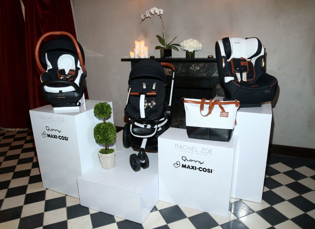 Maxi-Cosi car seats and bags displayed on a white platform on a black and white checkered floor.