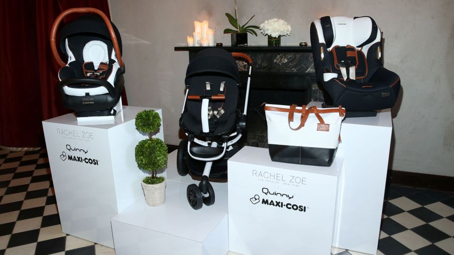 Maxi-Cosi car seats and bags displayed on a white platform on a black and white checkered floor.