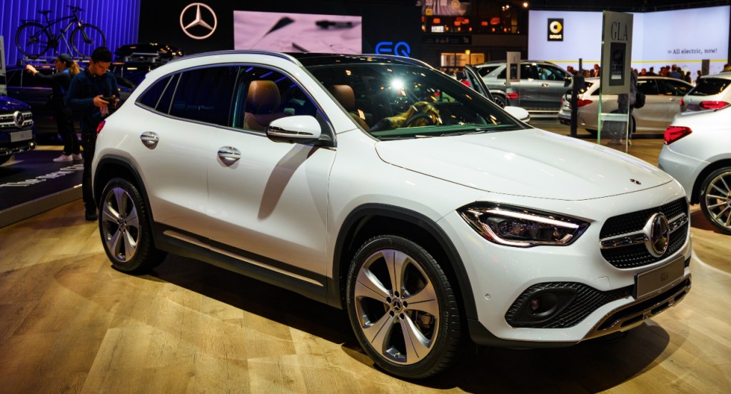 A white Mercedes-Benz GLA luxury SUV is displayed in a showroom. 
