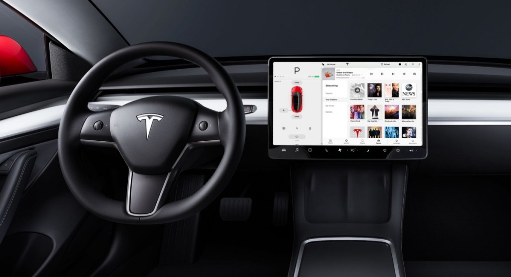 The steering wheel and screen of the inside of a Tesla Model 3. 