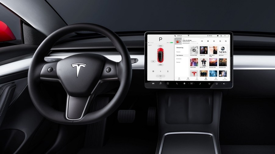 The steering wheel and screen of the inside of a Tesla Model 3.