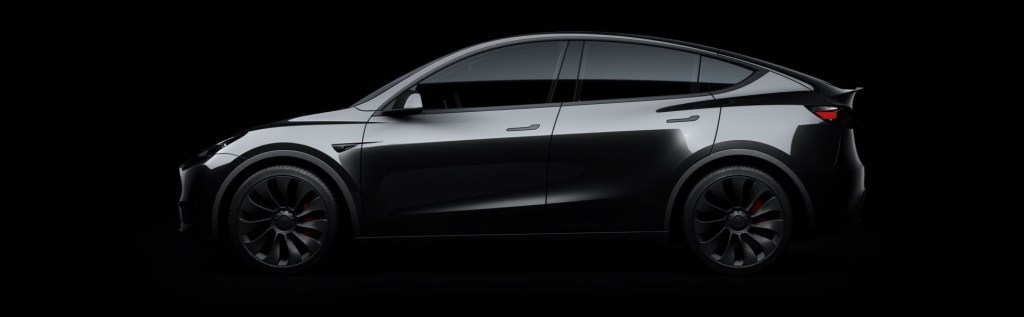 A dark gray 2021 Tesla Model Y against a black background. 