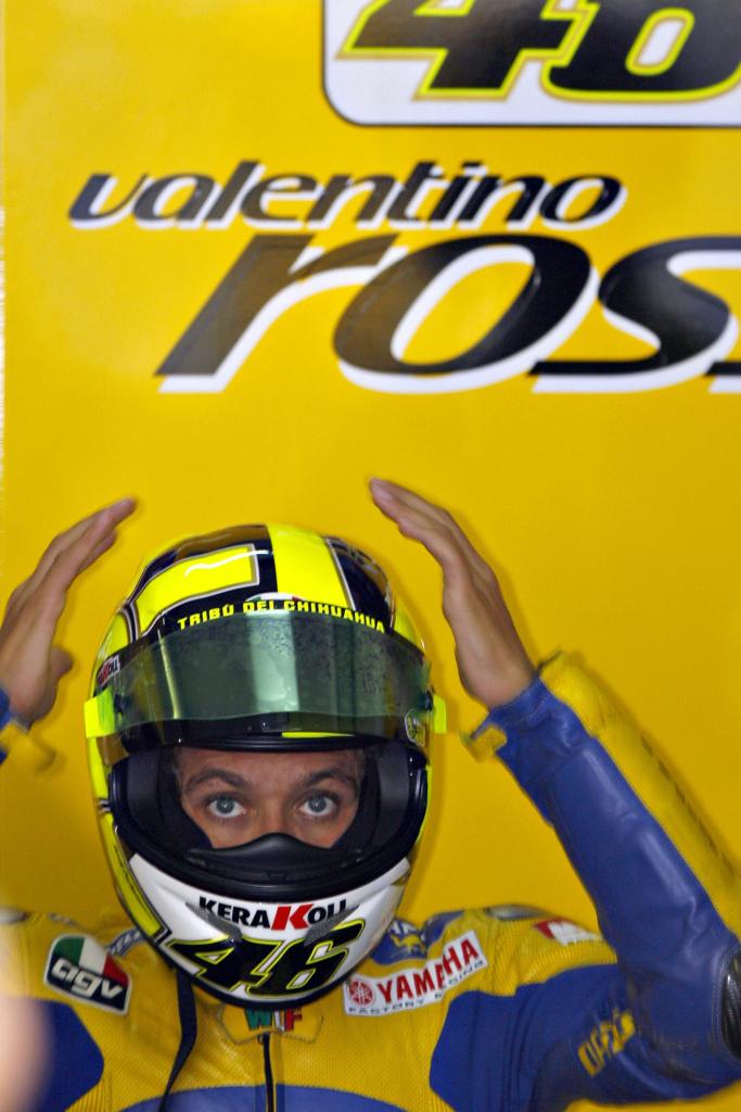 Blue-and-yellow-clad MotoGP racer Valentino Rossi checks how his motorcycle helmet fits at a 2006 Malaysian Grand Prix practice session