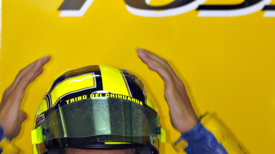 Blue-and-yellow-clad MotoGP racer Valentino Rossi checks how his motorcycle helmet fits at a 2006 Malaysian Grand Prix practice session