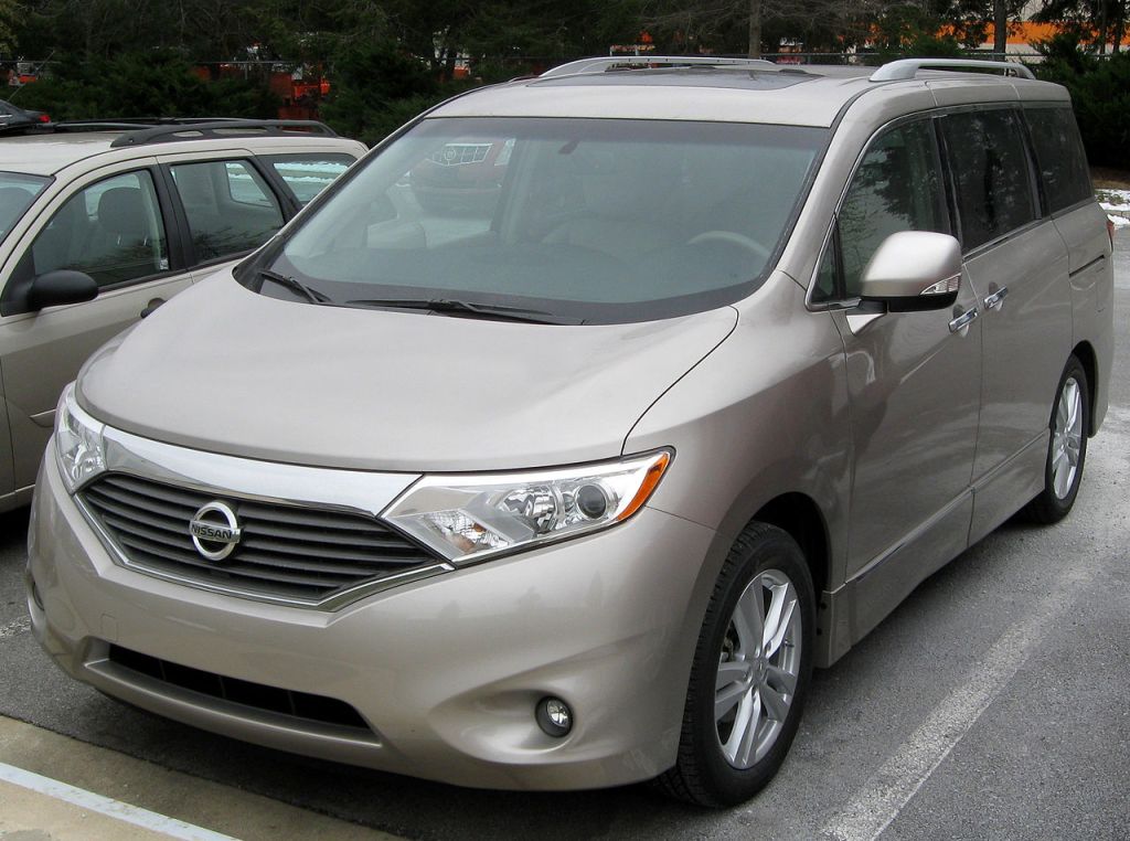 a gold 2011 nissan quest parked in a parking lot during the day