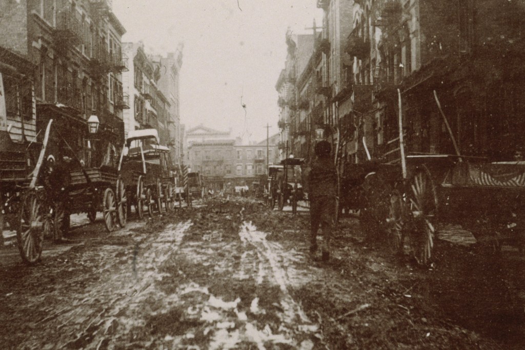 circa 1899: Carriages sit in the mud on either side of Willet Street between Stanton and Houston Street prior to the construction of 'Bone Alley Park,' New York City.