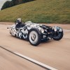 A black-white-and-gray camouflaged new Morgan 3-Wheeler testing on a highway