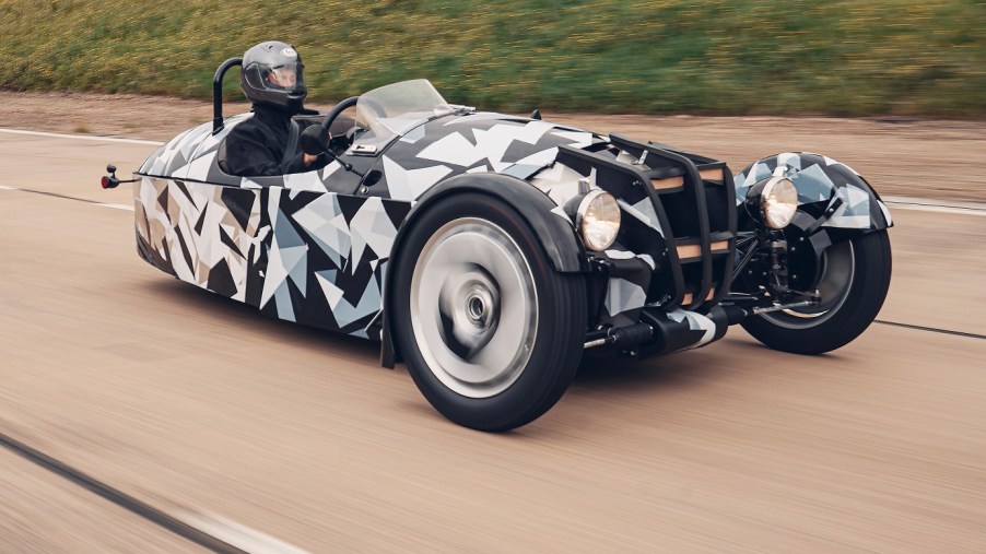 A black-white-and-gray camouflaged new Morgan 3-Wheeler testing on a highway