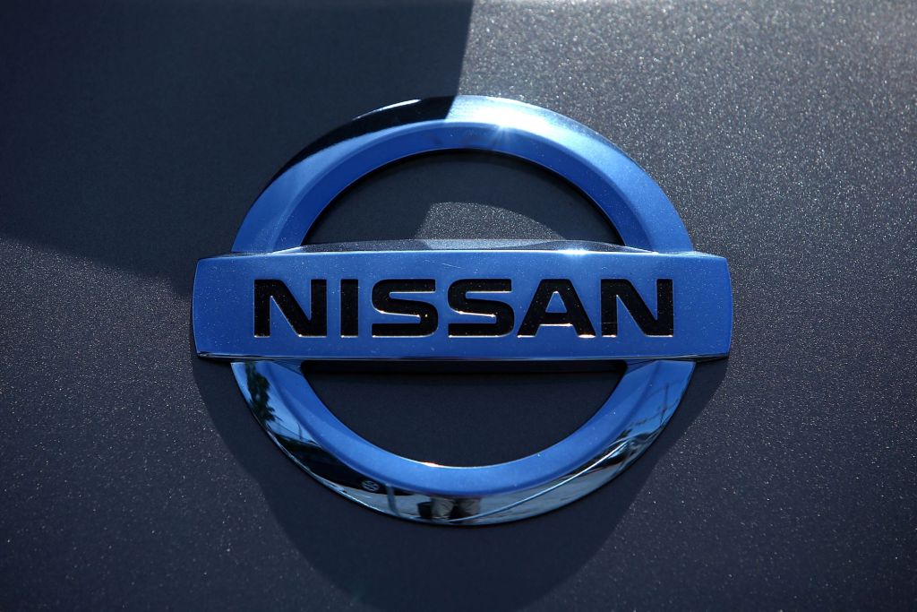 Chrome Nissan logo on a grey car.