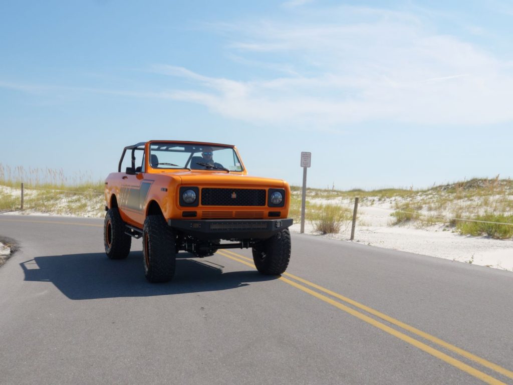 Orange and black 1979 International Harvester Scout driving by sand dunes