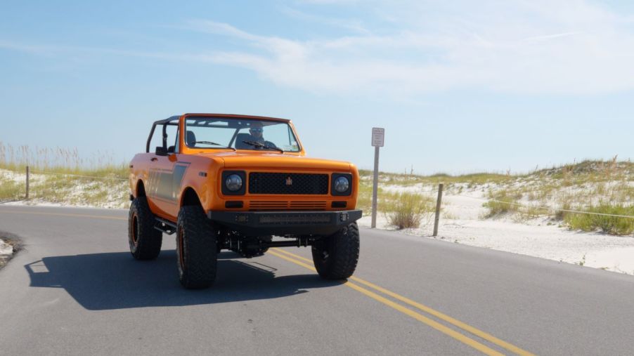Orange and black 1979 International Harvester Scout driving by sand dunes