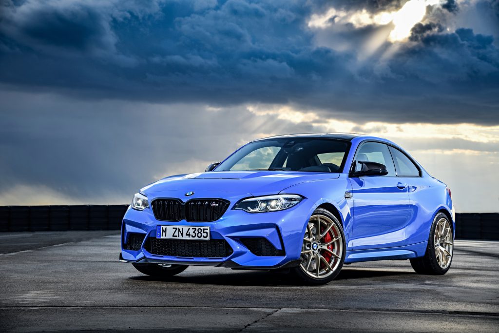 A blue BMW M2 CS on a runway just after a storm, the ground still wet with rainwater