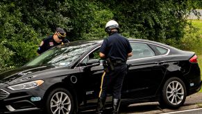 Two police officers pulling over a for unsafe or illegal activity black car.