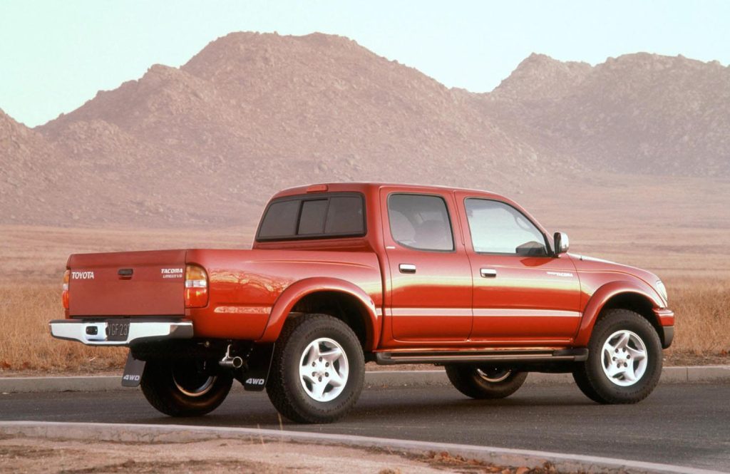 Red 2002 Toyota Tacoma with mountains in the background