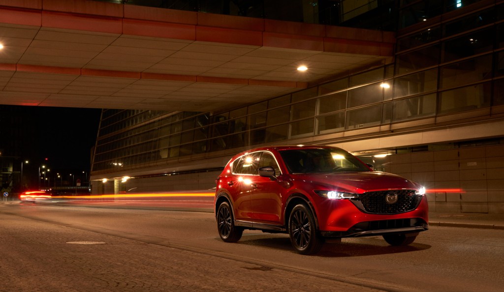 Red 2022 Mazda CX-5 driving by a large building at night