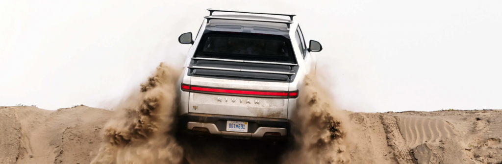 The Rivian R1T electric truck model driving on sand dunes
