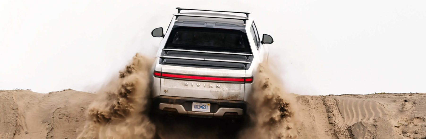 The Rivian R1T electric truck model driving on sand dunes