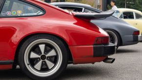 Side view of the rear halves of a red, gray, and yellow classic Porsche 911