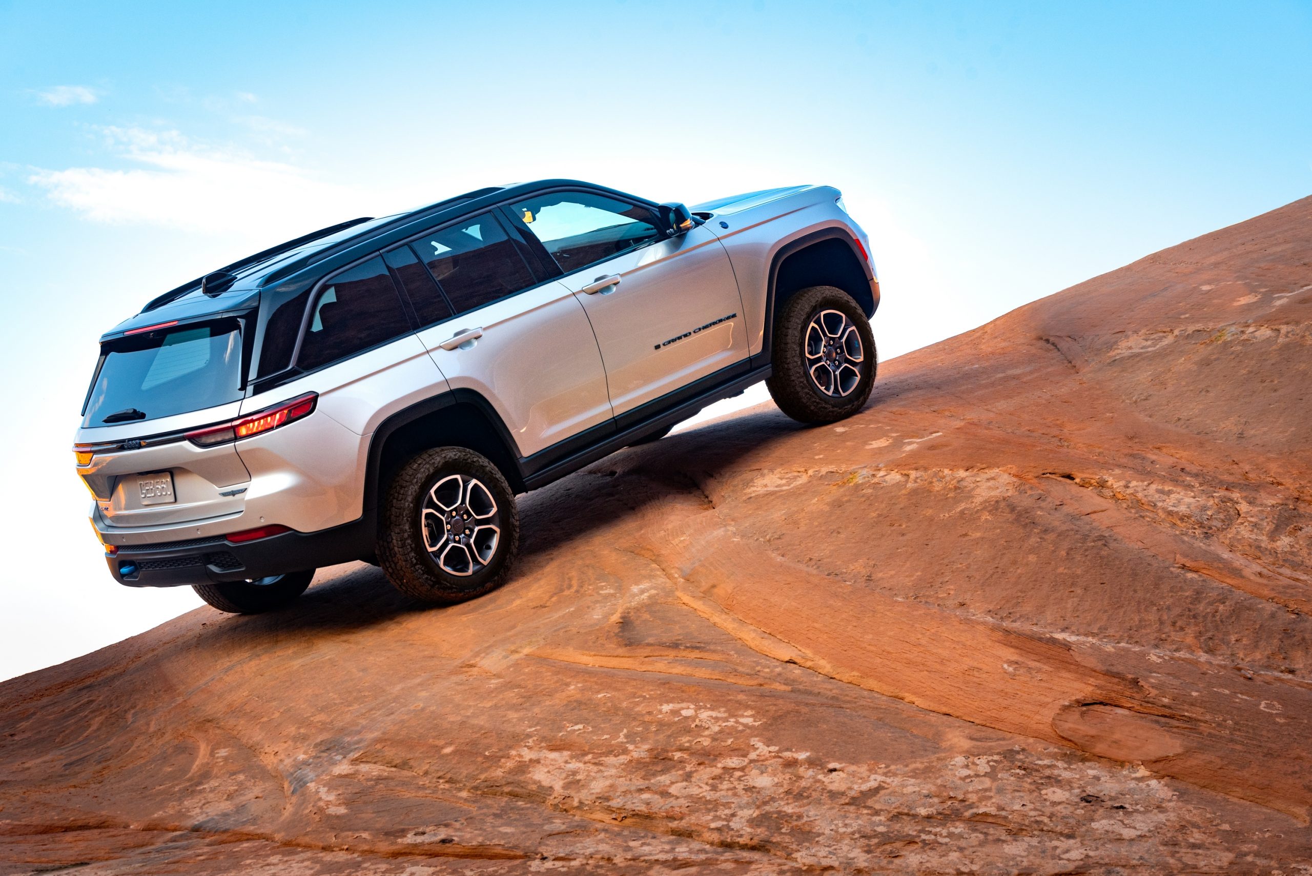 Silver 2022 Jeep Grand Cherokee 4xe driving up a hill