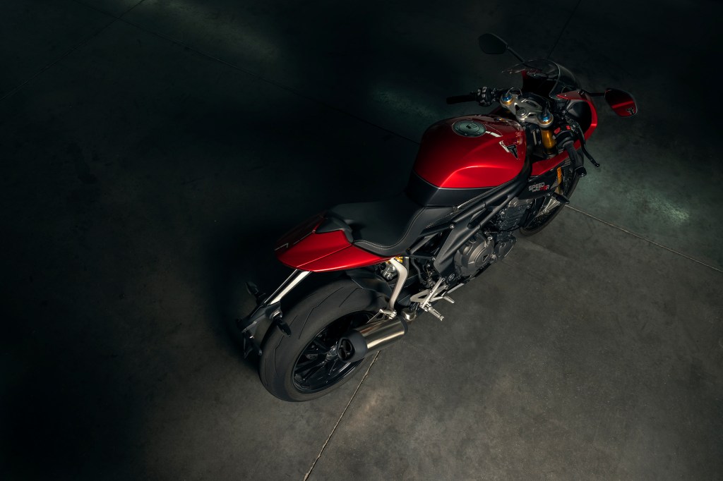 The overhead side 3/4 view of a red-and-black 2022 Triumph Speed Triple 1200 RR in a garage
