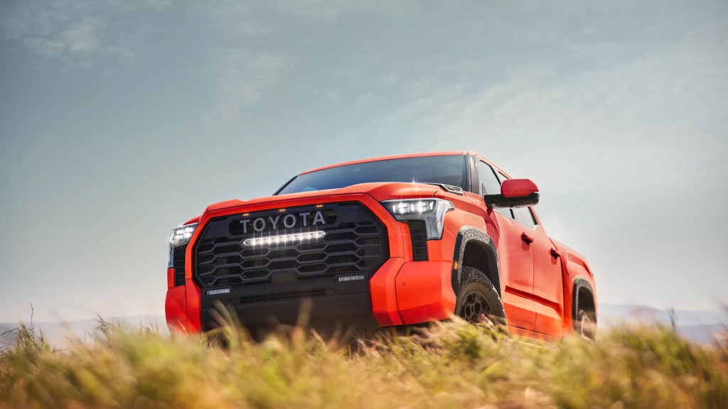 This is a promo photo of a 2022 Toyota Tundra TRD Pro parked in a field. This high-speed offroad truck is a cost-effective Ford Raptor