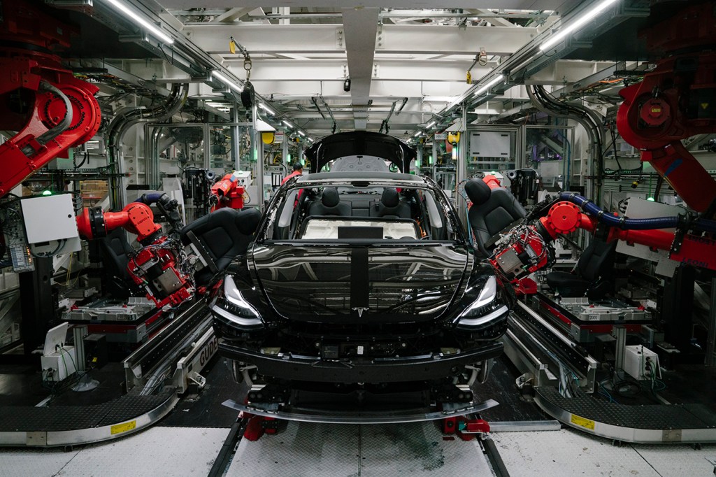 Robotics arms install the front seats to the Tesla Model 3 at the Tesla factory in Fremont, California. Tesla is one of the few automakers to not be hit hard by the global chip shortage