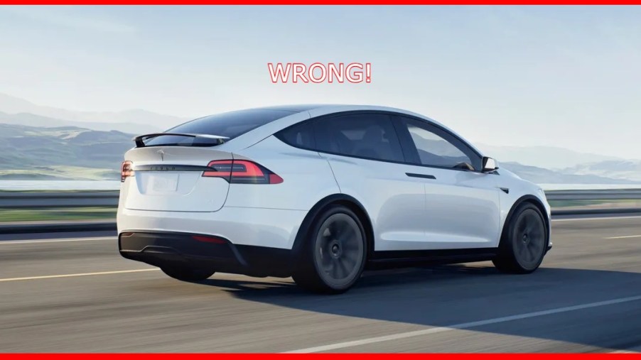 A white Tesla Model X electric SUV is driving on the road.